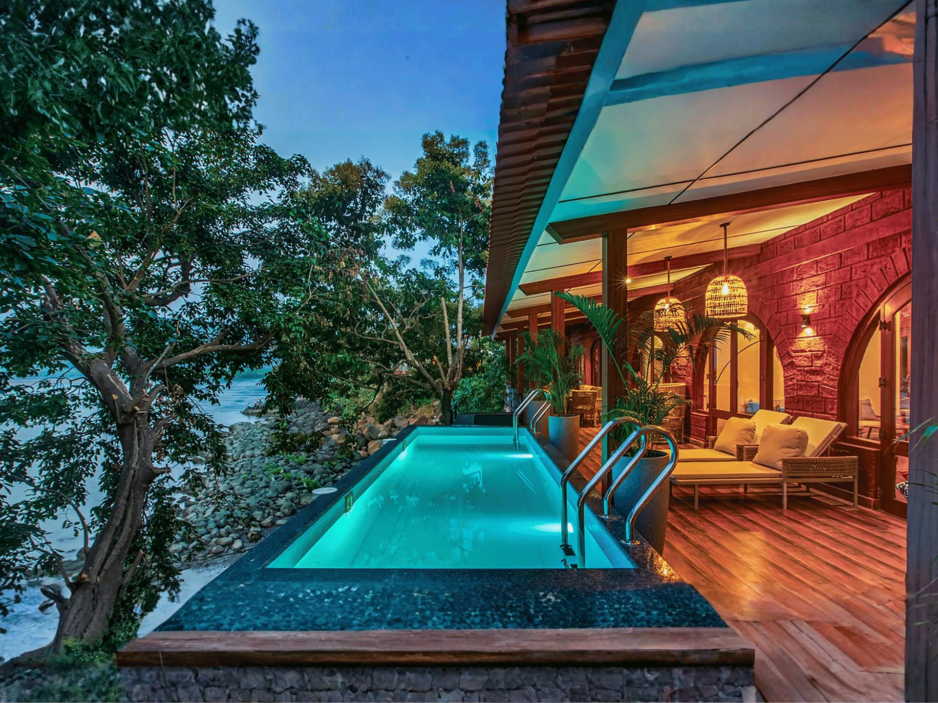 Lit infinity pool and timber deck of a beachfront Mulberry villa at dusk